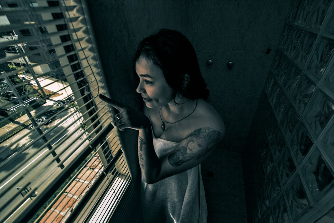 Jovem mulher brasileira escrevendo em um diário perto da janela